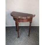 Antique flip-top table, the scalloped edged surface above a frieze, raised on turned legs ending