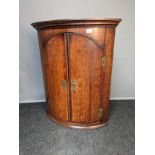 19th century oak corner cabinet, the moulded cornice above two doors with brass hinges and lock