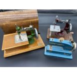 Three various miniature table top sewing machines. Grain sewing machine with lid carry case and