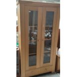 Large light oak two door display cabinet.