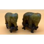 Two Chinese hand carved elephant sculptures sat upon wooden carved stands. [8cm high]