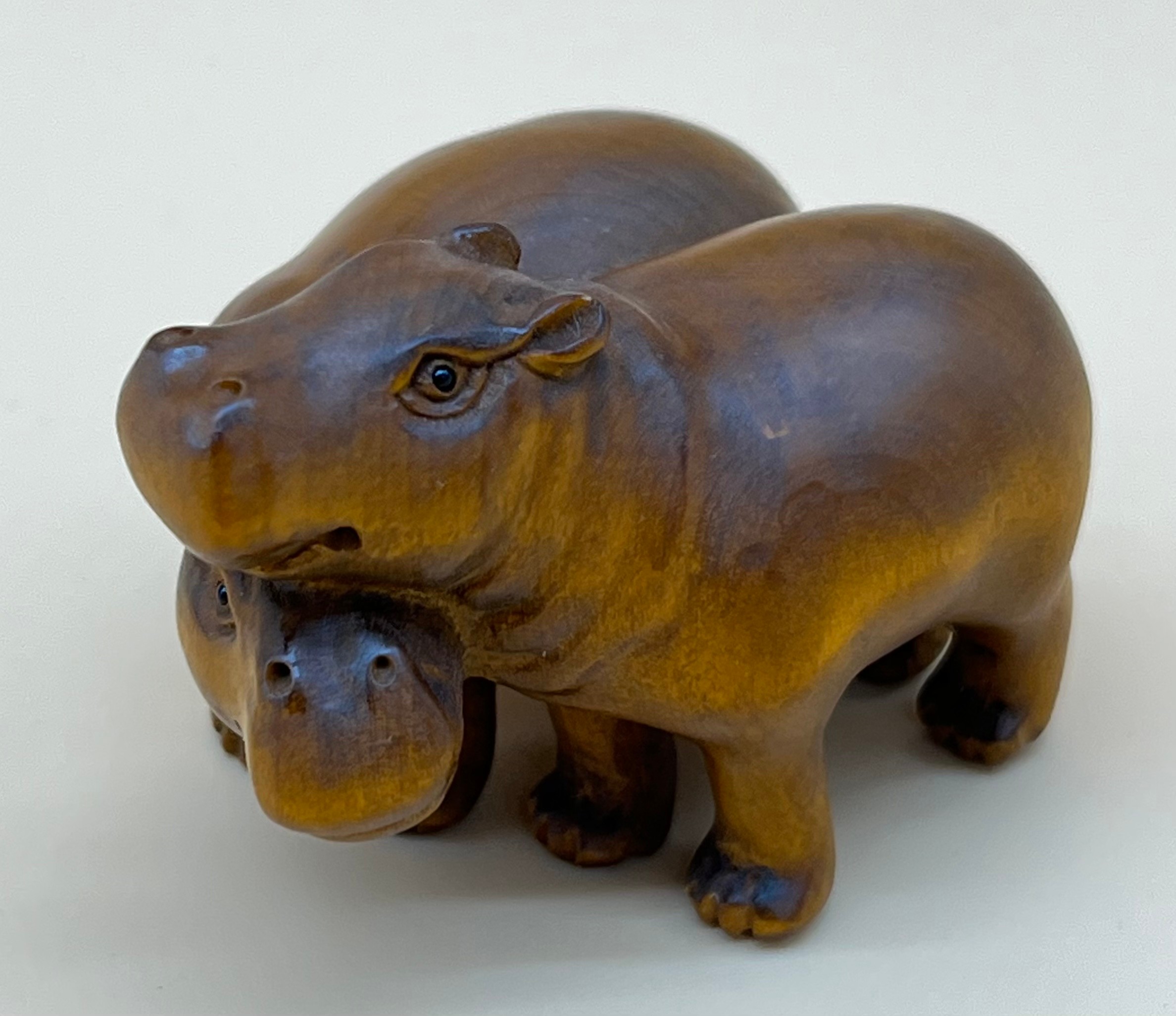 Japanese hand carved netsuke sculpture of a pair of hippos, both have black bead eyes and signed