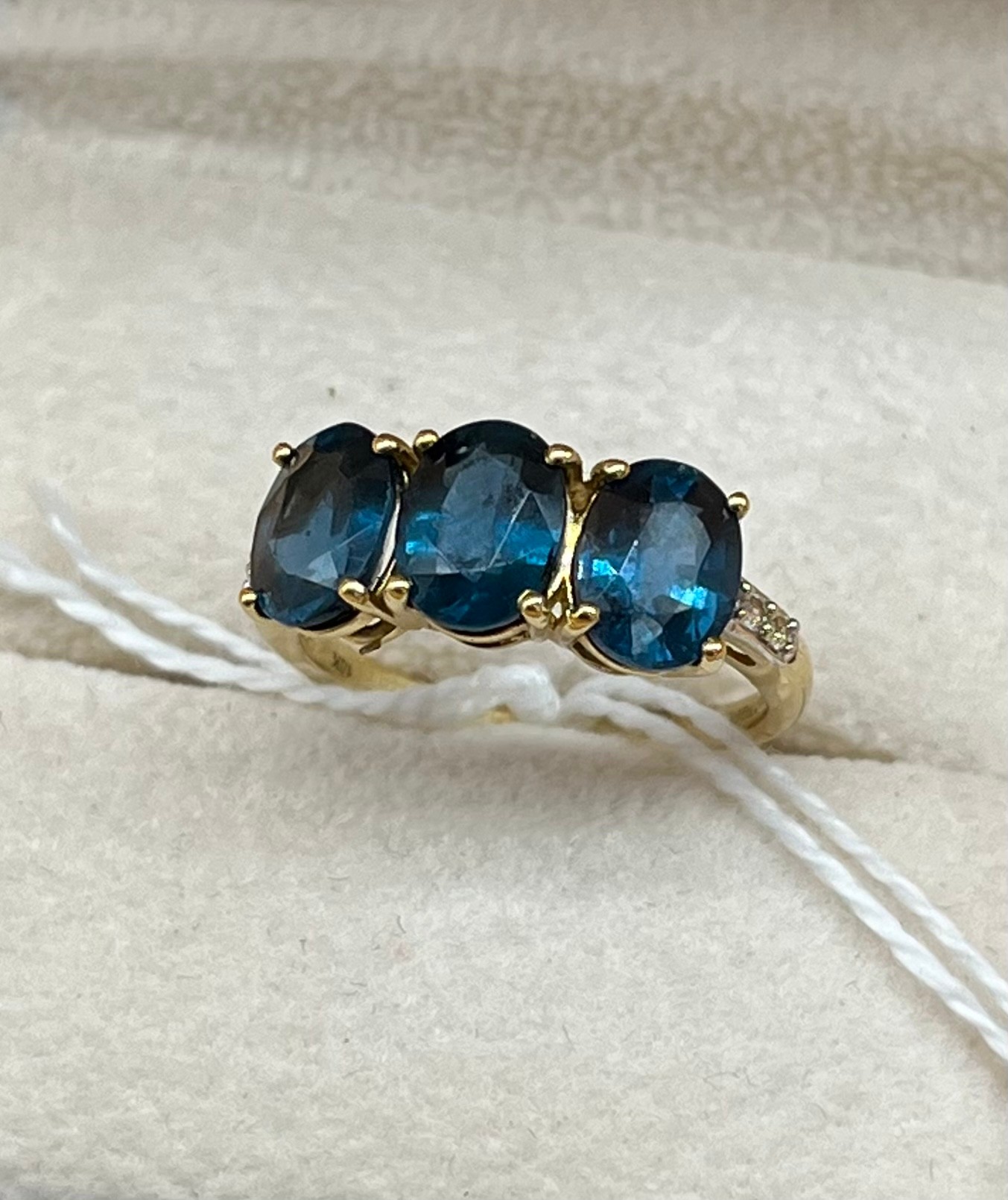 10ct yellow gold ladies ring set with three large blue topaz stones off set by small white spinel