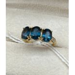 10ct yellow gold ladies ring set with three large blue topaz stones off set by small white spinel