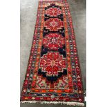 Antique large hand woven Persian style hall runner rug. Blue, red ground with orange trims. [