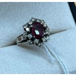 White gold/ platinum ladies diamond and ruby set ring. Fitted with 16 diamonds and one centre