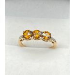 10ct yellow gold ladies ring set with three round cut orange tanzanite stones off set with diamond