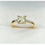 10ct yellow gold ladies ring set with a princess cut pale green topaz off set by diamond stone