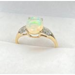 10ct yellow gold ladies ring set with an oval cut opalescent style centre stone off set by white