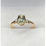 10ct yellow gold ladies ring set with a single oval cut pale green spinel stone off set by white