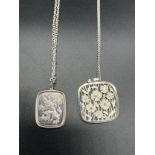 Two silver ornate pendants with silver chains. Rampart Lion pendant and flower design pendant.