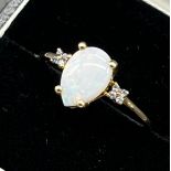9ct yellow gold ladies ring set with a pear drop cut opal stone off set by blue stone shoulders. [