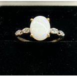 10ct yellow gold ladies ring set with a single oval cut opal off set by white topaz shoulders. [Ring