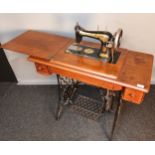 Antique pedal singer sewing machine, raised and supported on a cast iron base. [78x90x44cm]