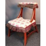 19th century prayer stool/ chair, upholstered in a floral material with brown fringe, raised on