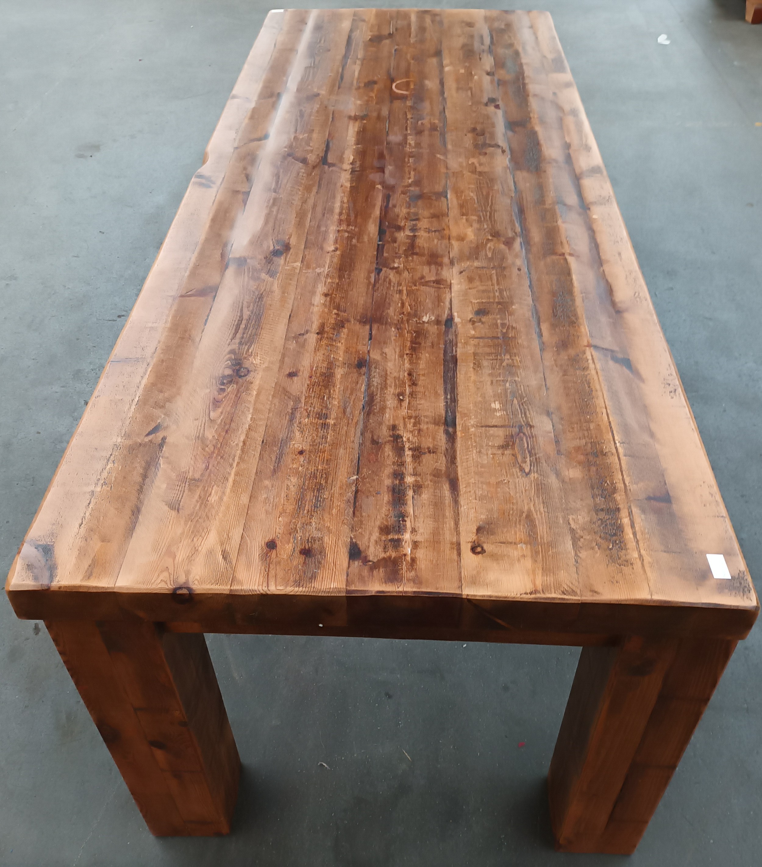 Solid rustic wood dining table, the long rectangular surface raised on square block legs [
