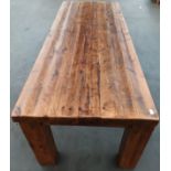 Solid rustic wood dining table, the long rectangular surface raised on square block legs [