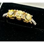 10ct yellow gold ladies ring set with three yellow stones off set by white spinel stone
