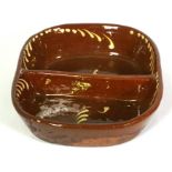 A slipware double sided baking dish, probably Welsh, 19th century, of oval form, with brown glaze