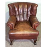 A George III style wing armchair, 20th century reproduction, with a deep filled cushion and squat