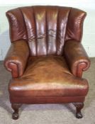 A George III style wing armchair, 20th century reproduction, with a deep filled cushion and squat