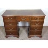 A George III style mahogany kneehole writing desk, with an plain rectangular top over an arrangement