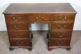 A George III style mahogany kneehole writing desk, with an plain rectangular top over an arrangement