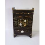 A small Japanese lacquered table top brush and trinket cabinet, Meiji period, with an arrangement of