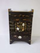 A small Japanese lacquered table top brush and trinket cabinet, Meiji period, with an arrangement of