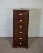 A narrow chest of six short drawers, varnished and with brass lipped cup handles