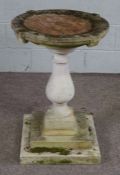 A composition stone bird bath, of dished form on a turned baluster pedestal base with stepped square