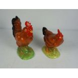 A pair of ceramic figures of a Cockerel and hen, both standing on green bases, Cockerel 24cm high (