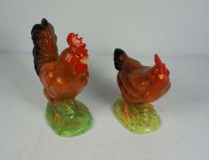 A pair of ceramic figures of a Cockerel and hen, both standing on green bases, Cockerel 24cm high (