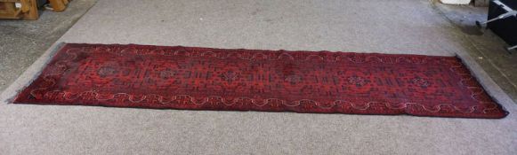 An Afghan Turkoman Khanmahkedi runner, with geometric medallions on a red field, within wavy border,