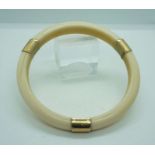 An 18 carat gold mounted ivory bangle, early 20th century, the plain hoop with three gold