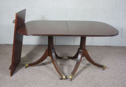 A George III style twin pillar mahogany extending dining table, circa 1900, with reeded top,