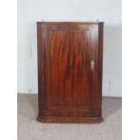 A George III mahogany corner cabinet, late 18th century, with a single fielded panelled door,