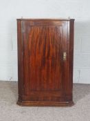 A George III mahogany corner cabinet, late 18th century, with a single fielded panelled door,