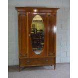 An Edwardian single wardrobe, with oval mirrored door and panelled sides, with a single long drawer,