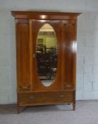 An Edwardian single wardrobe, with oval mirrored door and panelled sides, with a single long drawer,