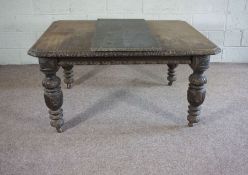 A late Victorian oak extending dining table, with carved border and set on cup and cover legs with