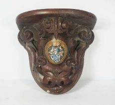 A Victorian carved wood clock bracket, inset with a shield and armorial, with motto ‘Arriere