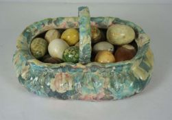 A large group of polished stone eggs, in various colours, set in a large ceramic basket, 50cm