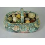 A large group of polished stone eggs, in various colours, set in a large ceramic basket, 50cm