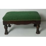 A small George III mahogany footstool, with green fabric top, the turned legs with hairy paw feet,