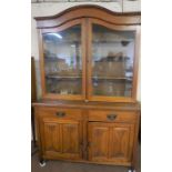 An Edwardian oak bookcase cabinet, with an arched top, with glazed doors and adjustable shelves on