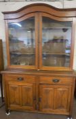 An Edwardian oak bookcase cabinet, with an arched top, with glazed doors and adjustable shelves on