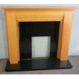 A modern birch veneered fire surround, with black slate inserts and base, 125cm high, 142cm wide