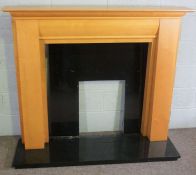 A modern birch veneered fire surround, with black slate inserts and base, 125cm high, 142cm wide