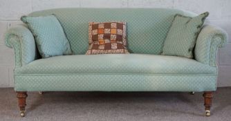 A small Victorian sofa, currently upholstered in jade green, with mahogany turned feet and brass